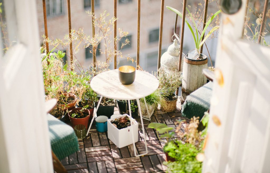 Small balkony with plants, decoration and a little table.