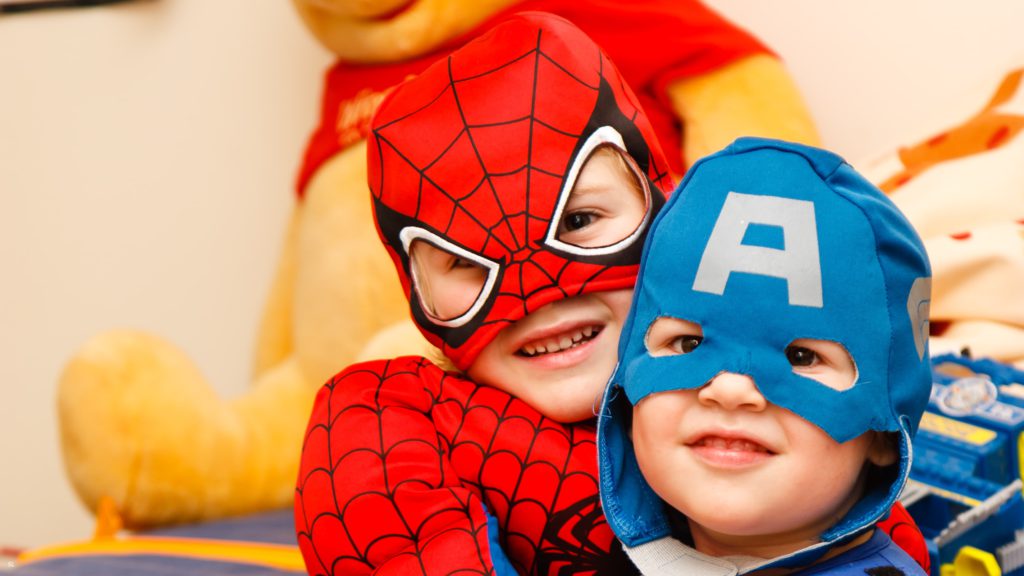 Two little boys, one with spiderman costume, the other one with captain america costume.